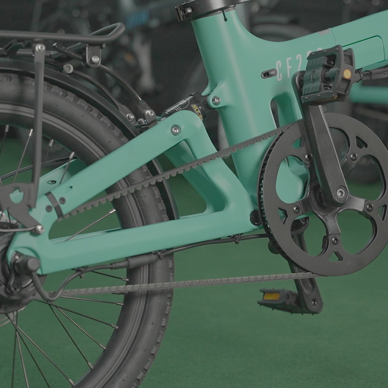 Close up image of the Turquoise Carbon Fibre 250 Folding E-Bike's drive belt and rear suspension components