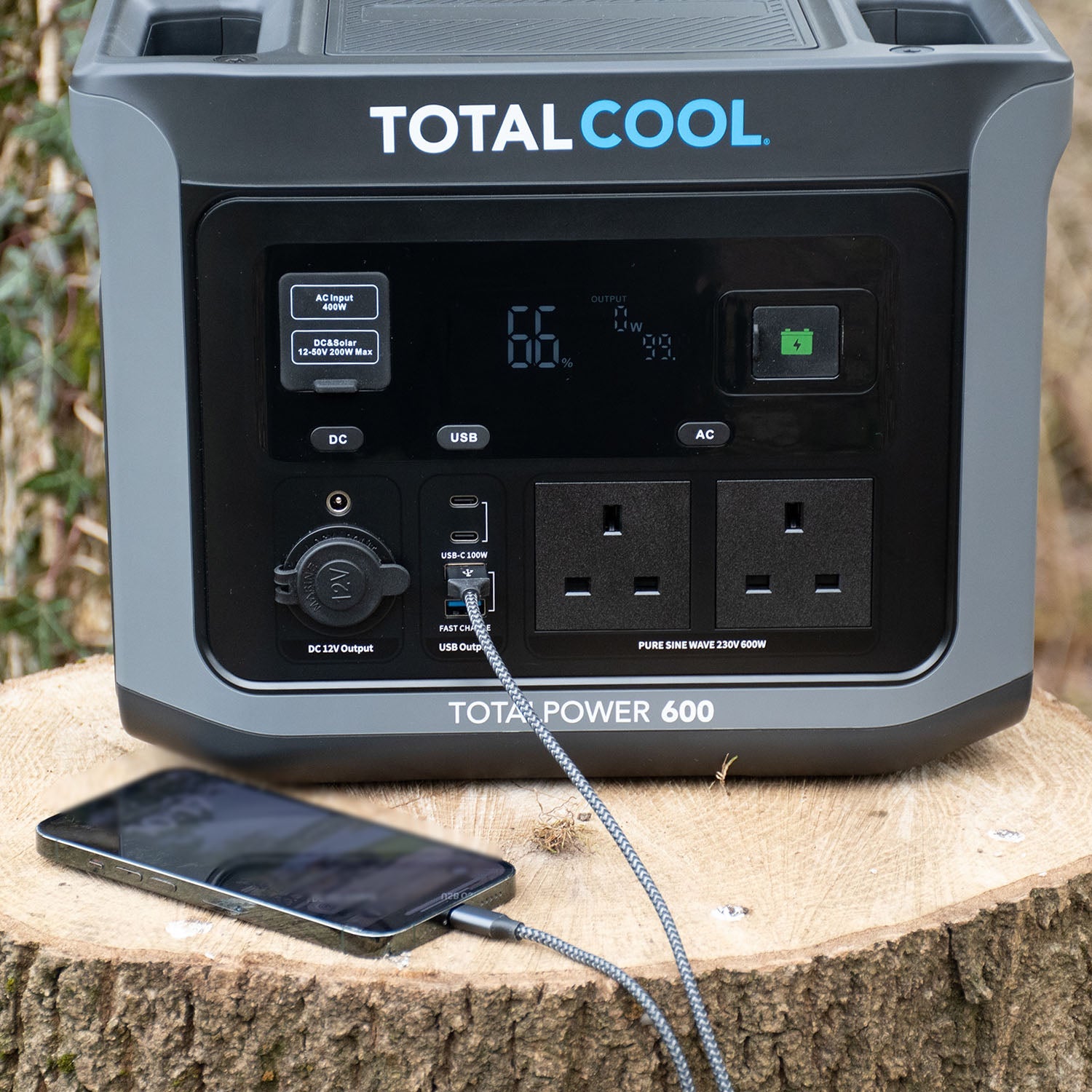 Image of Totalpower 600 charging a phone, viewed from an angle ontop of a tree trunk