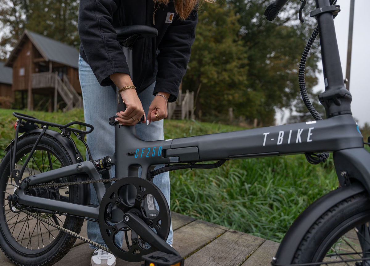 Lifestyle image of a woman operating the black Carbon Fibre 250 folding E-Bike's seat locking mechanism