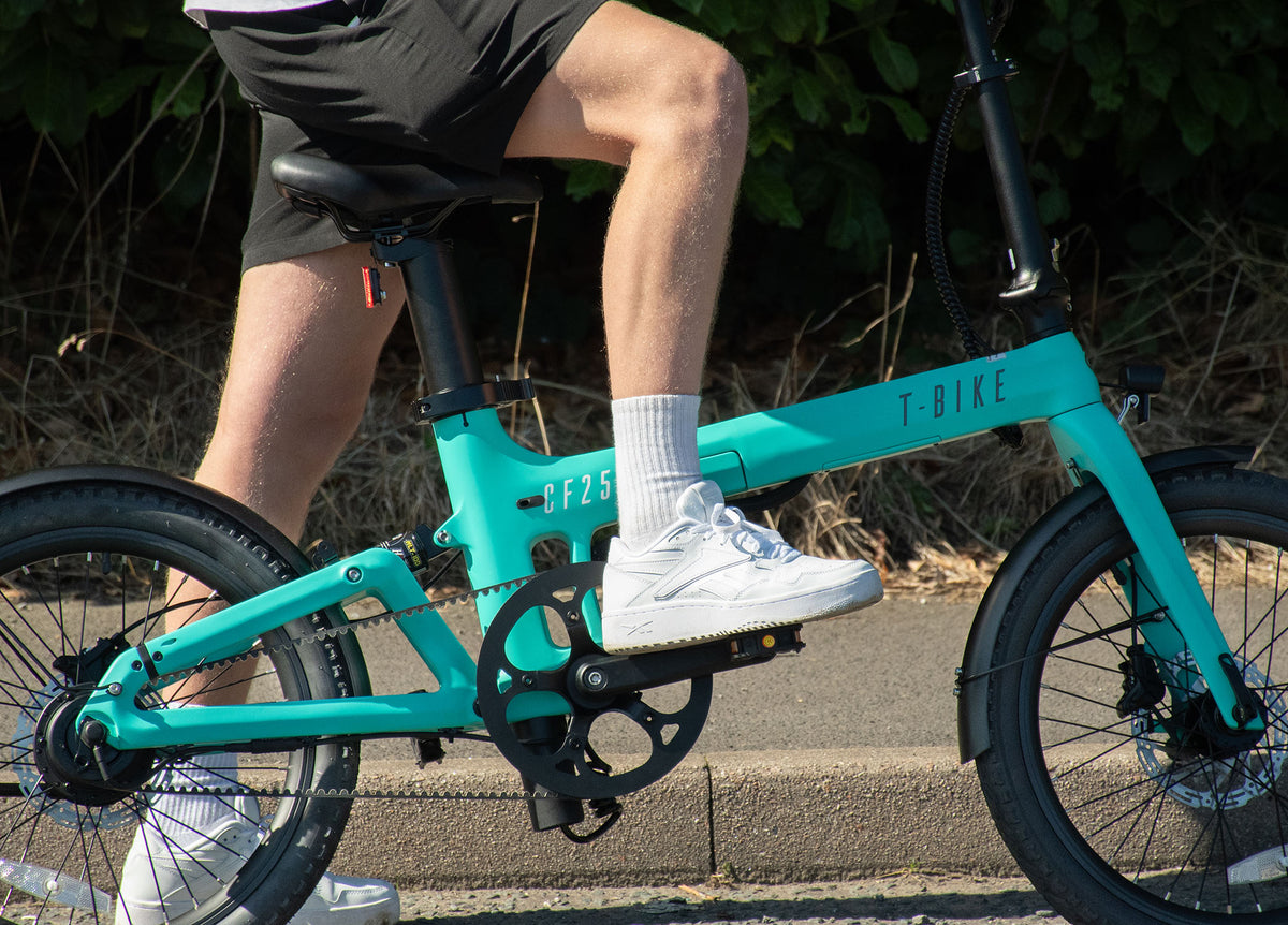 Lifestyle image of a man riding the Turquoise Carbon Fibre 250 folding E-Bike 